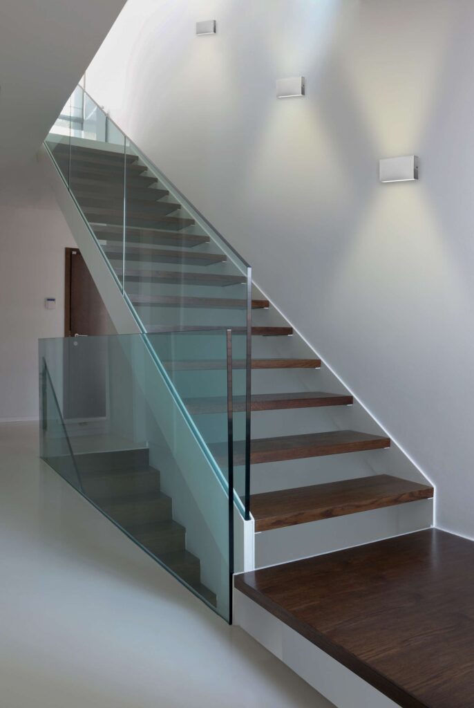 wooden stairs with glass balustrade in modern interior and white epoxy flooring